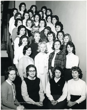 Posed group photograph of the Home Economics Club tiered on a staircase.