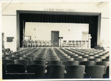 Sign over the stage reads 'Labor Omnia Vincit.'