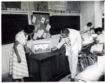 African-American instructor, T. W. Stanback, examines a set made by a student, Mrs. Callahan.