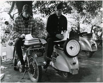'Chuck Jaco (1) and Jim Halley, University frosh, find their scooters provide a good place to study on warm September afternoons.'