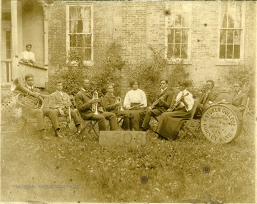 Group portrait of Storer College Cornet Band members with instruments on lawn. Pictured: 'B. Debbis, C. Dennis, John W. McKinney, T. Herrod, Trulia Jones, Eugene Jones, C. McKinney, Prof. Saunders, W. Harris.'