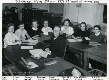 Group of scholarship students in the School of Journalism in a classroom.  From left to right: Kay Ellis, Diane Ash, Drema Wyat, Barbara Sayre, Budd Thalman, Martha Sandy, Ida Frances Ward and Janet Wallace.
