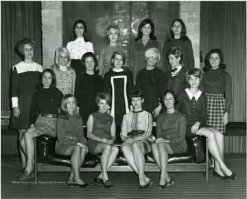 Female members of Panhellenic Council pose in front of a fireplace in Mountainlair. Some are named: Standing far left in a back row is Carolyn Peluso and Anna Ott stands next to her, the rest is unknown; in the middle row sitting far left is Nancy Davenport and the rest is unknown; in the bottom row, the second from right is Mary Fowler and the rest is unknown. 