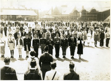 An assembly of R.O.T.C. cadets on a plaza (now Mountainlair Parking Area).  A row of cadets with different uniforms and sponsors are appeared to be receiving words.  In the background, Stewart Hall, Clark Hall and roofed stadium seats in where Mountainlair is located now are seen.