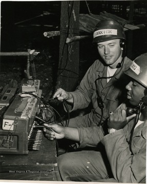 Two cadets in combat uniform at R.O.T.C. Summer Camp operate on a field telecommunication switch board. Please credit US Army Photograph if published.