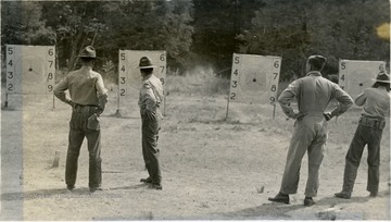 Four cadets appear to be inspecting targets they have prepared.