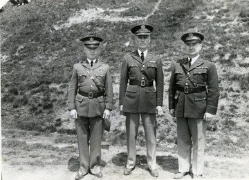 Three officers stand side by side by an embankment of Drill Field.
