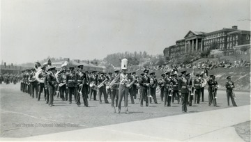 The R.O.T.C. band on the Drill Field. Spectators seated on the hillside below Stalnaker Hall.