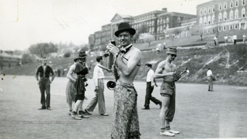 Cadets and band members dressed in costume; a saxophone player without a shirt  turns to pose for a photo.