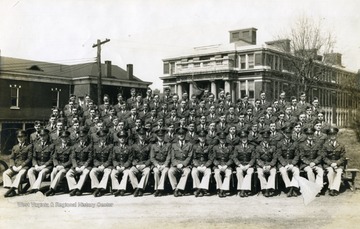 The cadets of company B sit on bleachers with officers for a group portrait in front of Oglebay Hall.