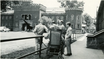 Army Cadets of Specialized Training Program chat near Mechanical Building; one cadet is in a wheel chair.