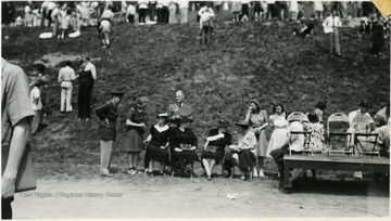 Women seated along the edge of the athletic / drill field.