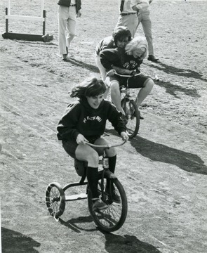Members of sororities race against each other on tricycles.
