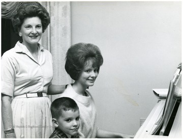 Standing: Mrs. Paul A. Miller, seated at piano Paula (WVU Class of 1967), and Tommy.