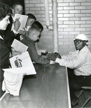 Armstrong, Louis, legendary jazz musician signs autographs for eager fans.