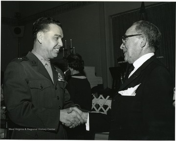 'WVU graduate and Marine Corps Brig. Gen. Earl E. Anderson shakes hands with Harry Goldsmith at WVU Birthday Dinner on Feb. 13, 1967.'