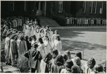 Sorority students circle around the Woodburn Circle and watch a procession of rows of students walk by.