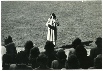 Female students who gathered around the Woodburn Circle sings at a direction of a female student.