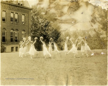 Female students of aesthetic dancing perform a dance with balls in hands.