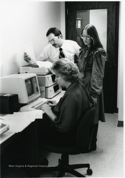 Jeannie Grimm at the computer and Susan Beates Hansen standing.