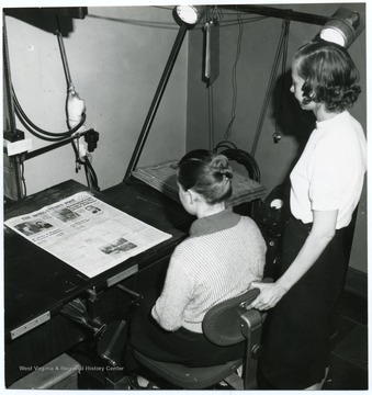 Mary Cain(standing) and Almeda Octken (seated) at a photo duplication machine.