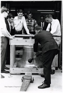 With assistance from members of Alpha Phi Omega, a service fraternity, Joe Gluck helps unpack the bell of battle cruiser West Virginia:  Doug Ritchey (left); John Liston (right); Dan Blosser (third from left).