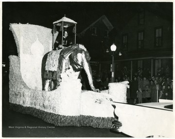 A Football player rides on a float with a golden elephant. 