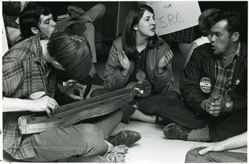 The person clapping is Pat Samargo; and on the left with the mustache is Harry Shaw, an anti-war activist.