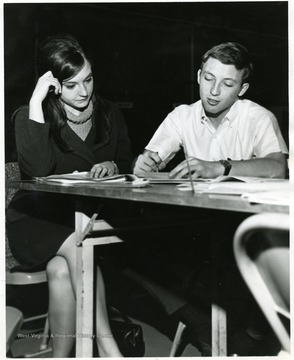 Two students possibly working on their registration forms.