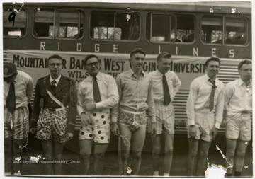 Members of the WVU marching band pose along with the band bus.