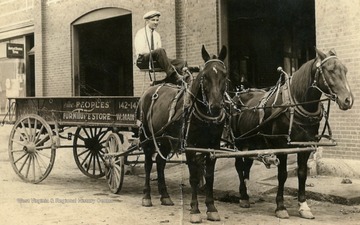 Man on horse drawn wagon outside of the Old Buick Garage on Water Street in Clarksburg, West Virginia.