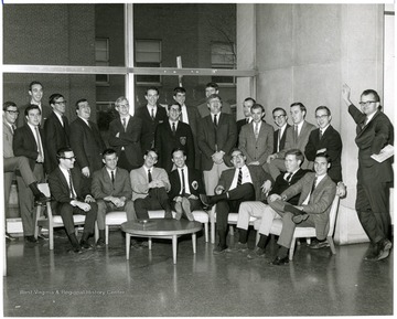 Standing in window frame in back center on left is Tim Barker, and the second person on Tim's  right is Jerry Clark. The man standing in center in second row back with glasses, dark hair, and a patch on his jacket is Terry Warley.