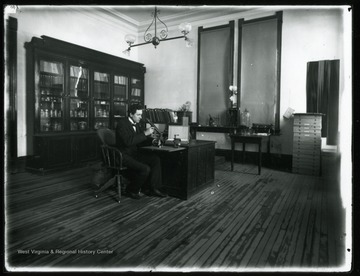 A. D. Hopkins handles a microscope in a room in the Agricultural Experiment Station.