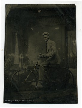 A portrait of student, Dille, Thomas R. riding a bicycle appears to be taken at studio.