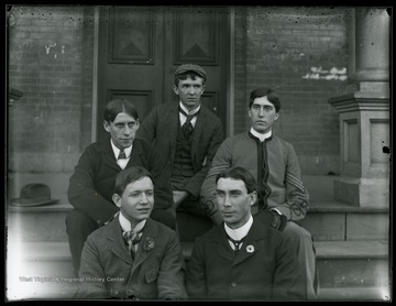 Five students pose on the steps in front of a building. 