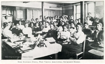 A view of female students and instructors in a Home Economics classroom.