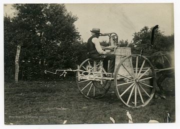 A man rides on a spray cart at Guseman's orchard.