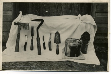 'Tools used for treating collar blight. Jar contains bi-chloride, pail, paint.  The tool next to trowel is a farrieis.  The tool between knife and gauge is a home-made scraper.'