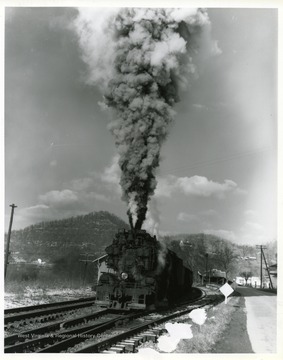 Image from the collection of the Chesapeake and Ohio Historical Society. 'CSPR-3698: H-6 2-6-6-2 Mallet #1307 starting coal train on Logan branch in 1955, high straight column of exhaust.'