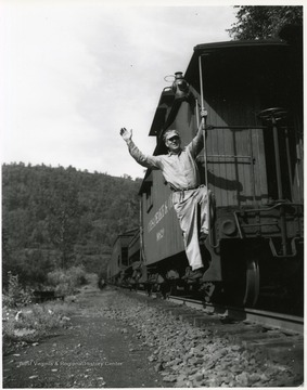 Image from the collection of the Chesapeake and Ohio Historical Society. 'CSPR-311: Brakeman signals from rear of C. &amp; O. Caboose #90820 on rear of Piney Creek branch coal train near Stanaford, W. Va.'