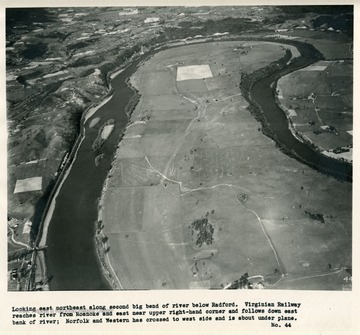 'Looking east northeast along second big bend of river below Radford.  Virginian Railway reaches river from Roanoke and east near upper right-hand corner and follows down east bank of river; Norfolk and Western has crossed to west side and is about under plane.'