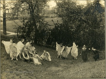 Student performers in togas. One is wearing a horse or donkey head mask.  Taken on school property.