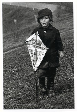 Holding a kite made of newspapers.