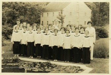 Choir group of girls from 4-H Harrison county camp in front of a pond in a garden.