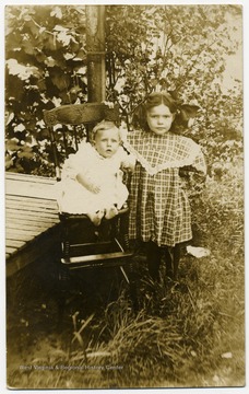 A baby seated and a young girl standing.