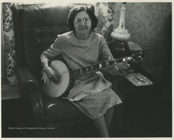 Aunt Jenny Wilson in her living room holding a banjo in her lap. 