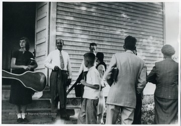 Singers and musicians standing on the steps of a church holding musical instruments. Left to right:  Ann Martin, Denver Lewis, Gary McDaniels, John Martin, Jr., Flo Jasper, Lucian McDaniels, and Dorothy McDaniels.