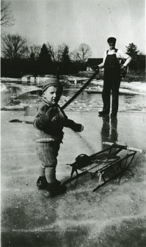 A picture of a man with a saw, Latch Dillion (?), and a child, Warren Ellison on the ice.