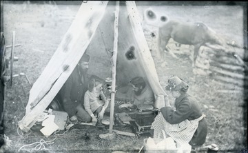 A picture of two men, a woman, and a child gathered around a tent for a meal. '32.D.(18); July 11, 1884, Friday 6:30 am, clear'