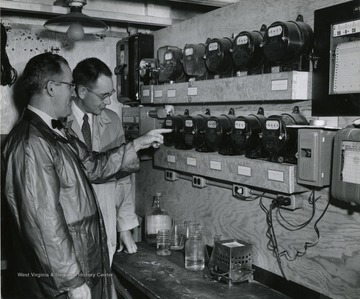 A photograph of Helford Longhouse (left), one time chairman of Agriculture Engineering Department, examining meters with another individual.